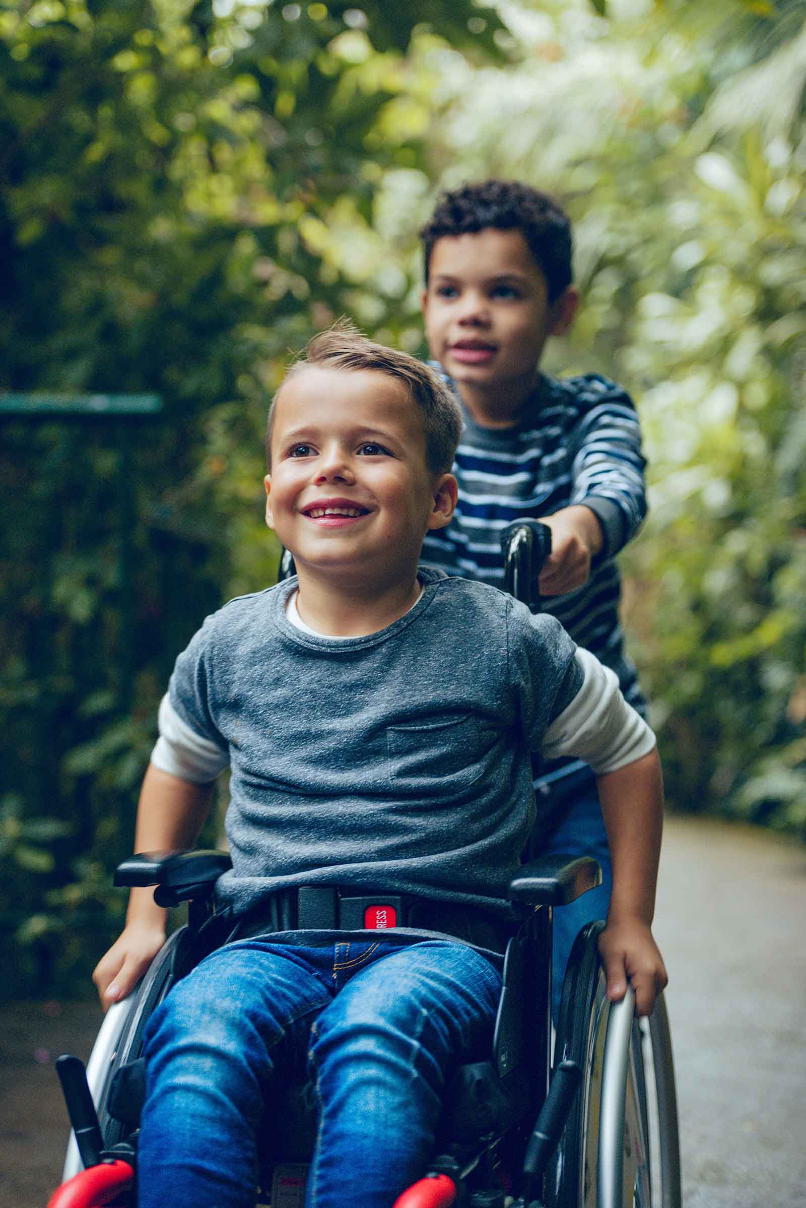 A boy in a wheelchair being pushed by a friend