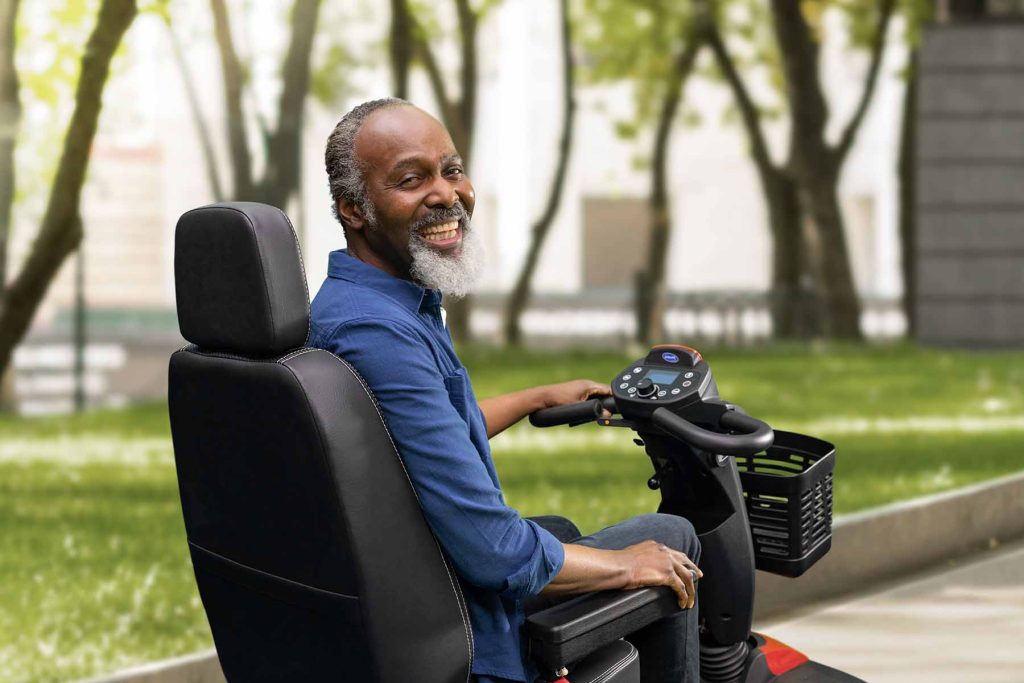 Man looking at camera on an Invacare Mobility Scooter in park